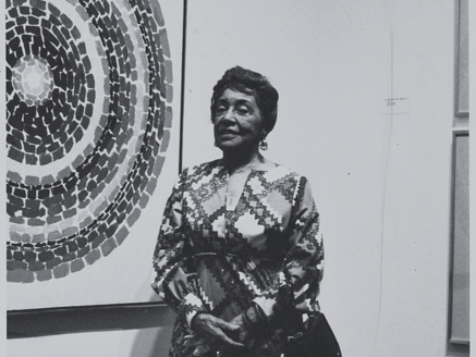 Portrait of Alma Thomas standing in front of a painting